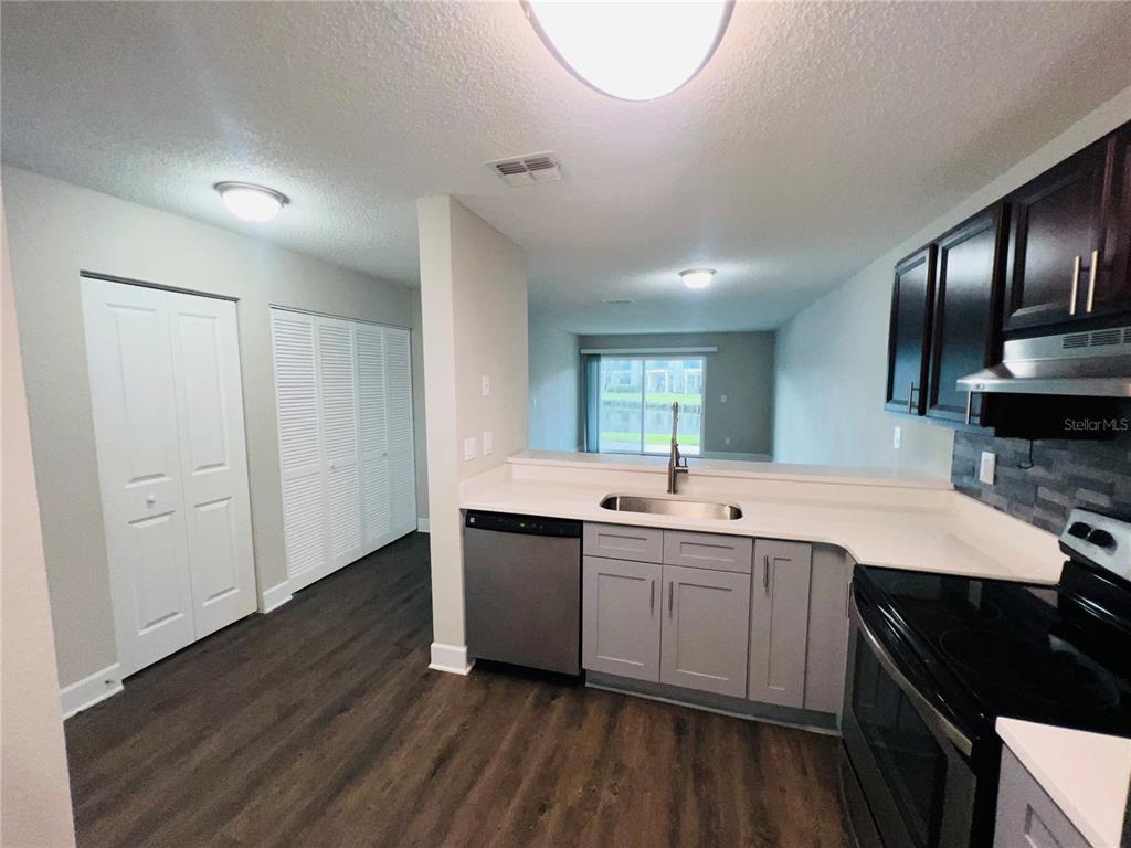 A kitchen with gray lower cabinets, dark upper cabinets, and a stainless steel dishwasher — 2556 WOODGATE BOULEVARD UNIT 103, ORLANDO, FL