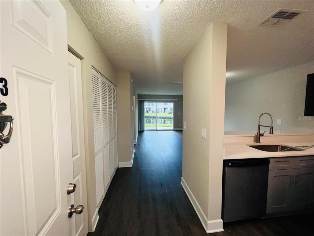 An entryway leads past a kitchen with gray cabinets toward a living area with sliders — 2556 WOODGATE BOULEVARD UNIT 103, ORLANDO, FL