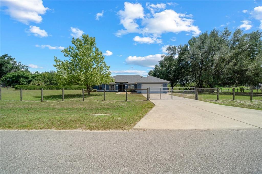 A single-story house with a garage sits behind a fenced yard and concrete driveway — 11985 SE 123RD AVENUE, OCKLAWAHA, FL