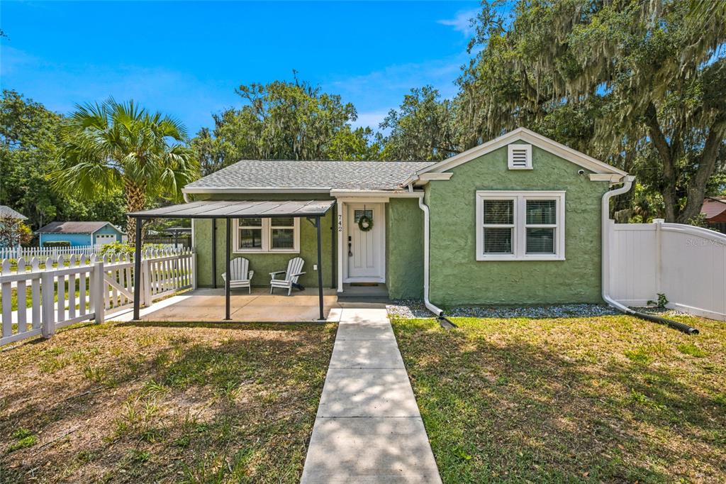 A green stucco house features a front porch, white fence, and a concrete walkway — 742 SE 12TH STREET, OCALA, FL