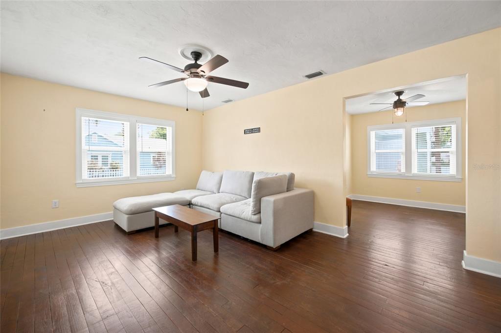 A living room with hardwood floors, a light-colored sectional sofa, and two ceiling fans — 742 SE 12TH STREET, OCALA, FL