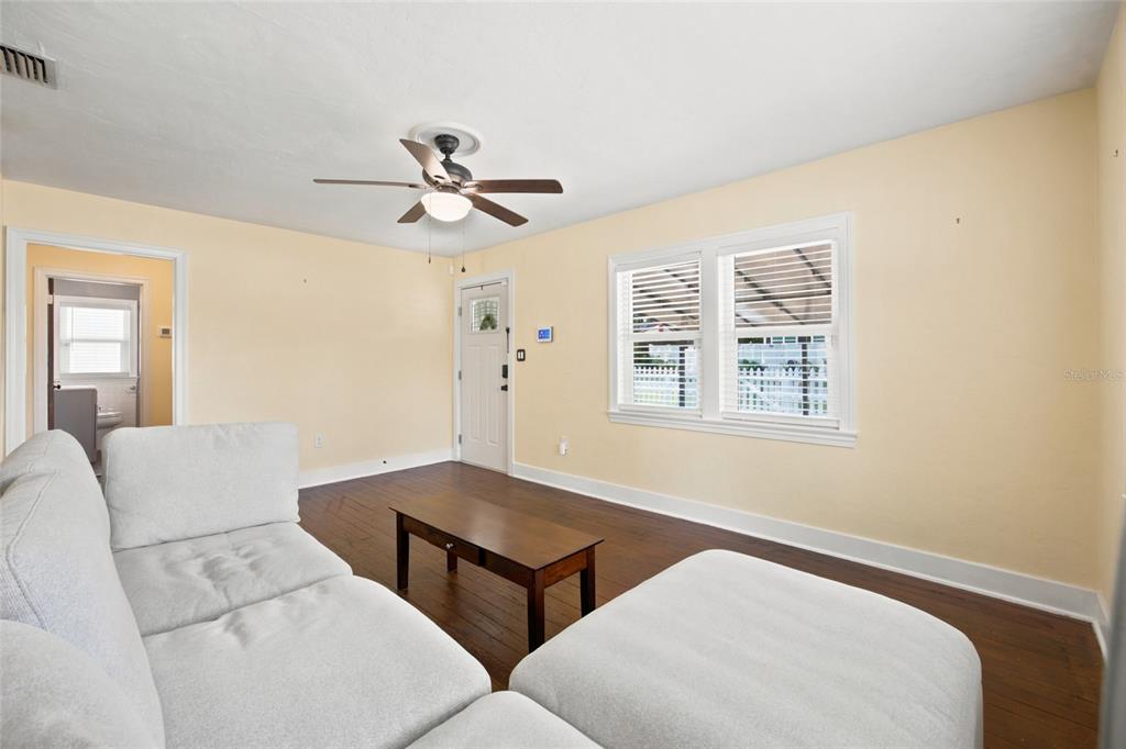 A living room features light yellow walls, dark wood flooring, a ceiling fan, and white furniture — 742 SE 12TH STREET, OCALA, FL