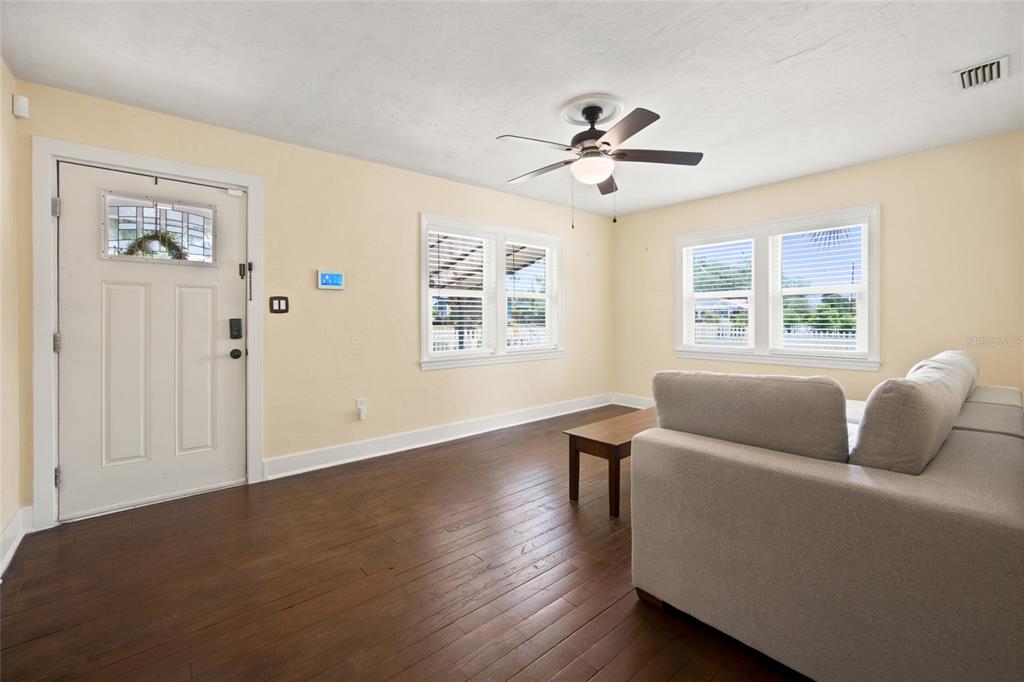 A living room with light yellow walls, dark hardwood floors, a ceiling fan, and white sofa — 742 SE 12TH STREET, OCALA, FL