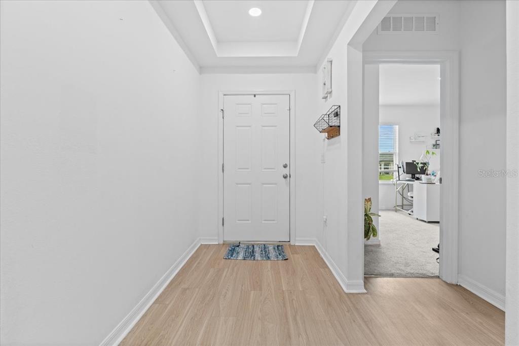 A bright entryway features light wood-look flooring, white walls, and a tray ceiling — 3476 BREWSTER ROAD, NORTH PORT, FL