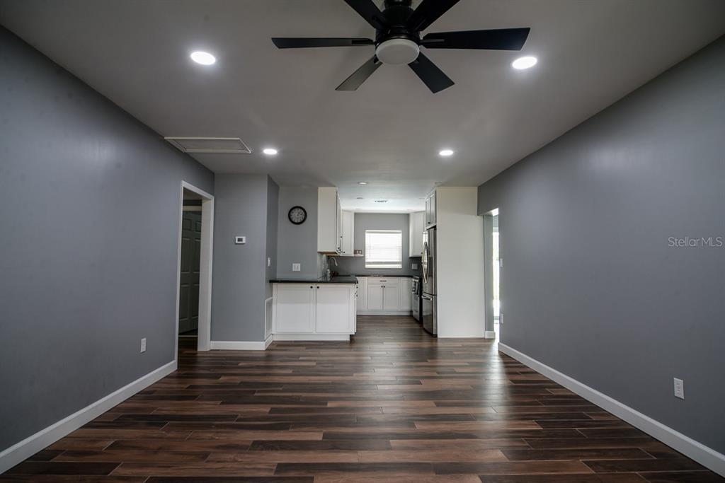A kitchen with white cabinets and dark countertops opens into a living area with gray walls — 103 DELLWOOD DRIVE, KISSIMMEE, FL