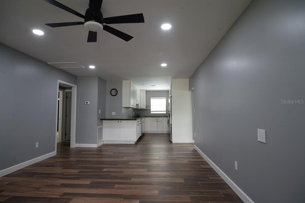 A kitchen with white cabinets and dark countertops opens into a gray-walled living area — 103 DELLWOOD DRIVE, KISSIMMEE, FL