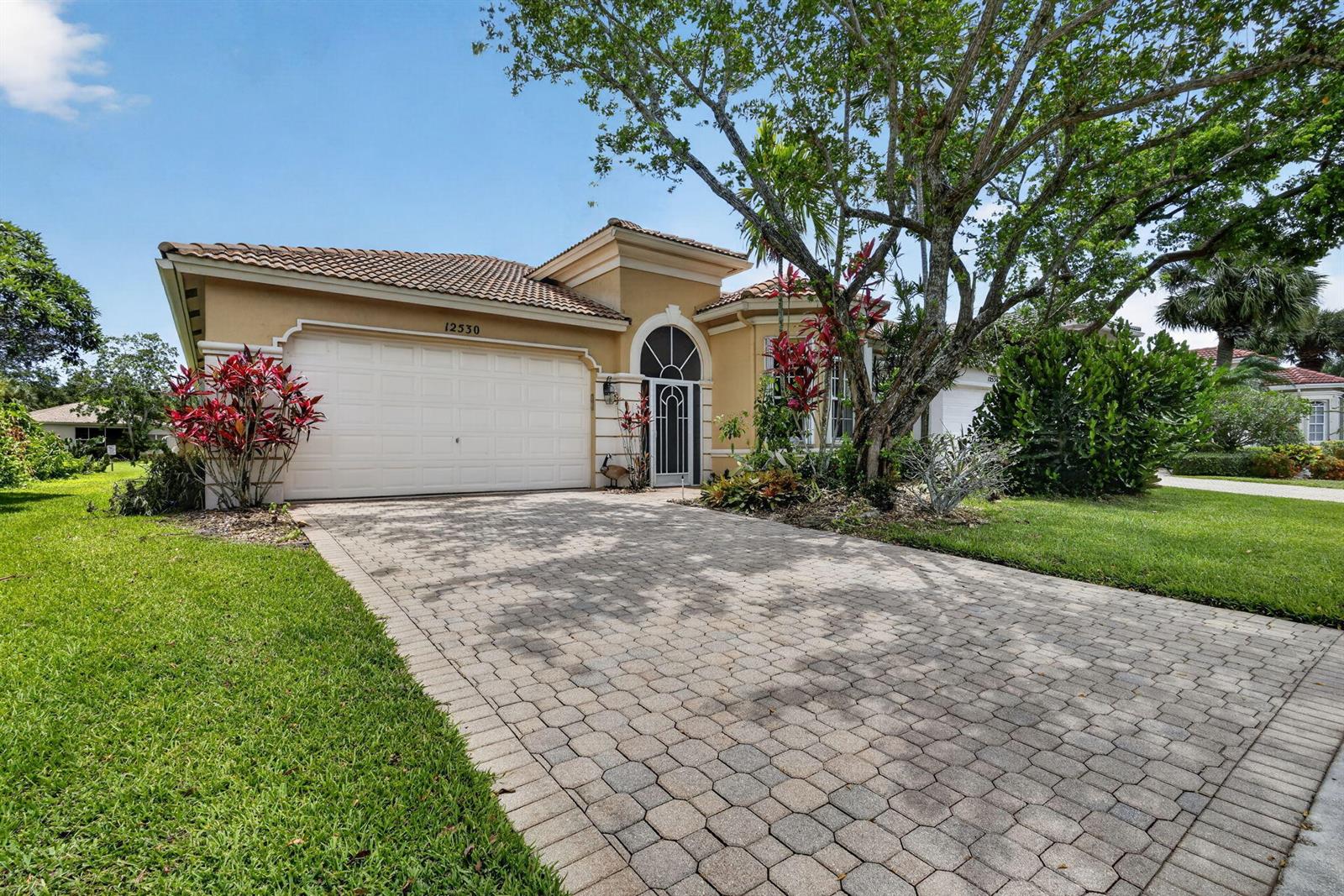 A single-story house with a paved driveway, two-car garage, and mature landscaping — 12530 Vía Valenza, Boynton Beach FL 33436, BOYNTON BEACH, FL