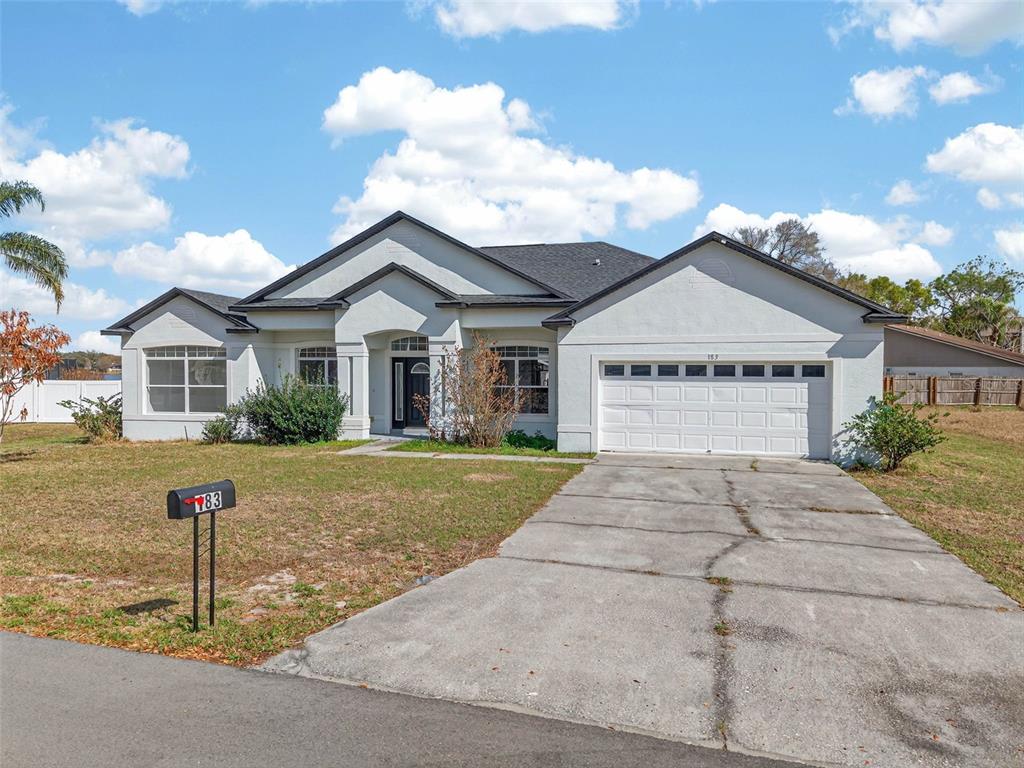 A single-story house with a white stucco exterior, a dark roof, and a concrete driveway — 183 LAKE THOMAS, WINTER HAVEN, FL