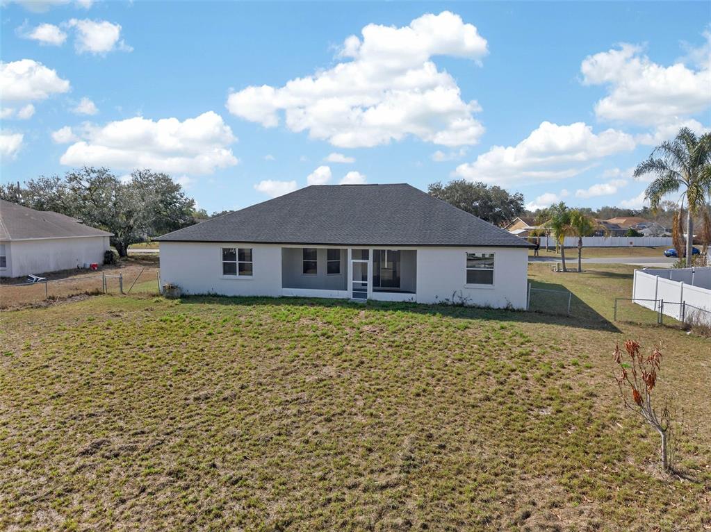 The rear exterior of a single-story house features a screened-in porch and a large yard — 183 LAKE THOMAS, WINTER HAVEN, FL