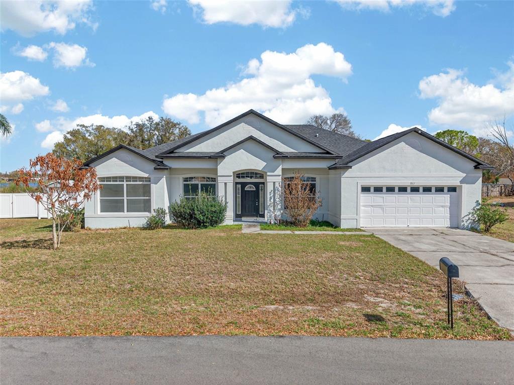 A single-story white house with a dark roof and a two-car garage — 183 LAKE THOMAS, WINTER HAVEN, FL