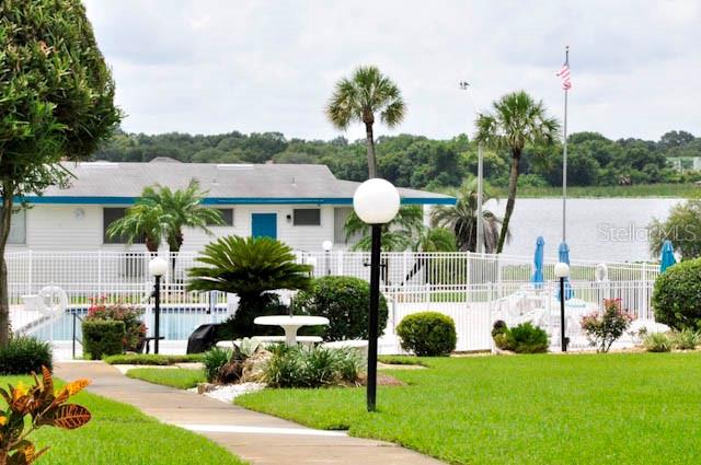 A white building with a pool and palm trees sits beside a lake — 1600 W LAKE PARKER DRIVE UNIT B4, LAKELAND, FL