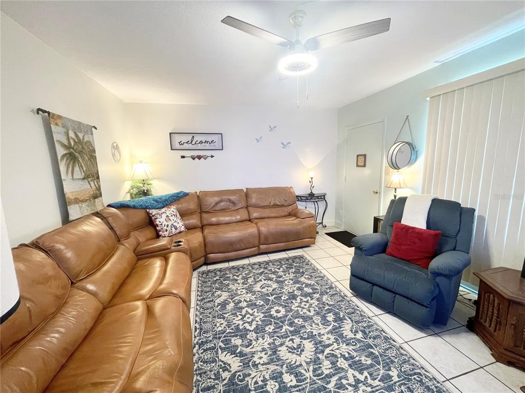 A living room features a large brown sectional sofa, a blue recliner, and a patterned rug — 1600 W LAKE PARKER DRIVE UNIT B4, LAKELAND, FL