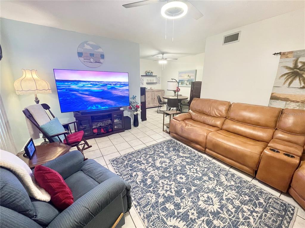 A living room features a large television, a brown leather sofa, and a blue rug — 1600 W LAKE PARKER DRIVE UNIT B4, LAKELAND, FL