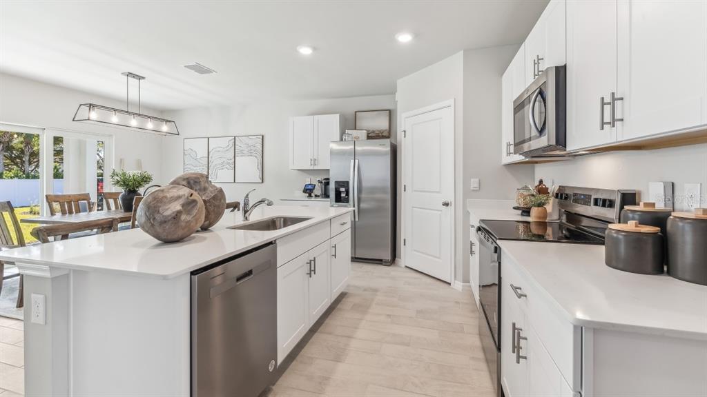 A modern kitchen features white cabinets, stainless steel appliances, and a large quartz-topped island — 16332 NAVARRO COURT, PUNTA GORDA, FL