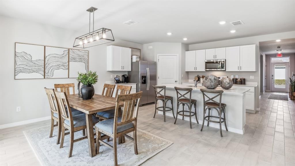 A dining area with a wooden table and chairs sits beside a modern white kitchen — 16332 NAVARRO COURT, PUNTA GORDA, FL