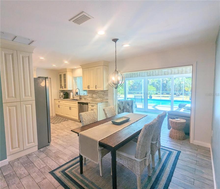 A dining area with a wooden table sits adjacent to a kitchen with cream cabinets — 3070 GULF GATE DRIVE, SARASOTA, FL