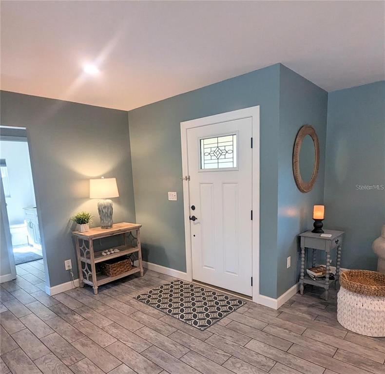 An entryway features blue walls, a white front door, and wood-look tile flooring — 3070 GULF GATE DRIVE, SARASOTA, FL