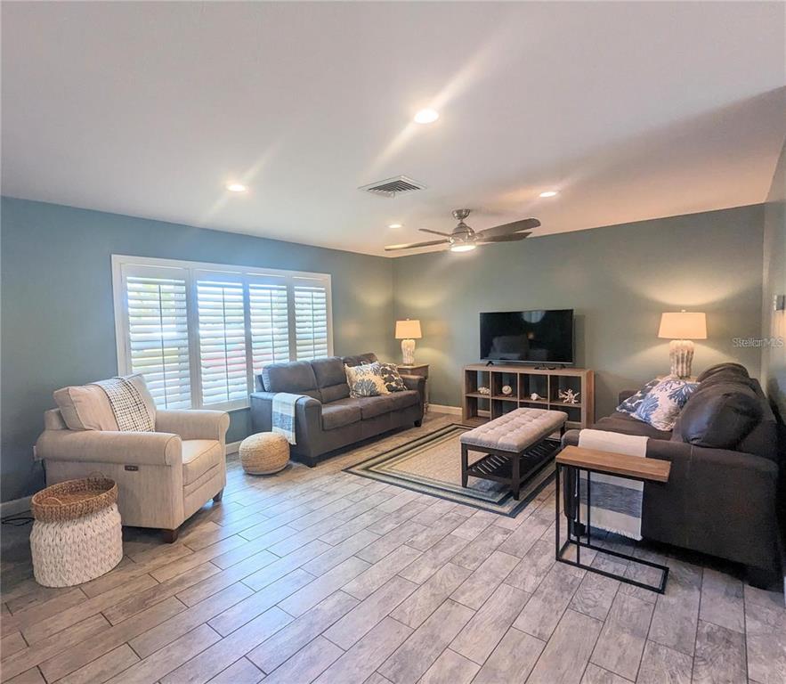 A living room features gray sofas, a beige armchair, a television console, and tile flooring — 3070 GULF GATE DRIVE, SARASOTA, FL