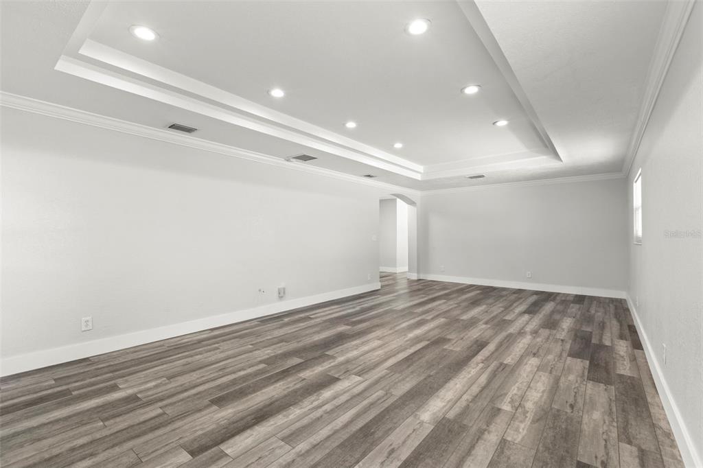 An empty room features gray wood-look flooring, white walls, and a recessed tray ceiling — 4510 68TH AVENUE N, PINELLAS PARK, FL