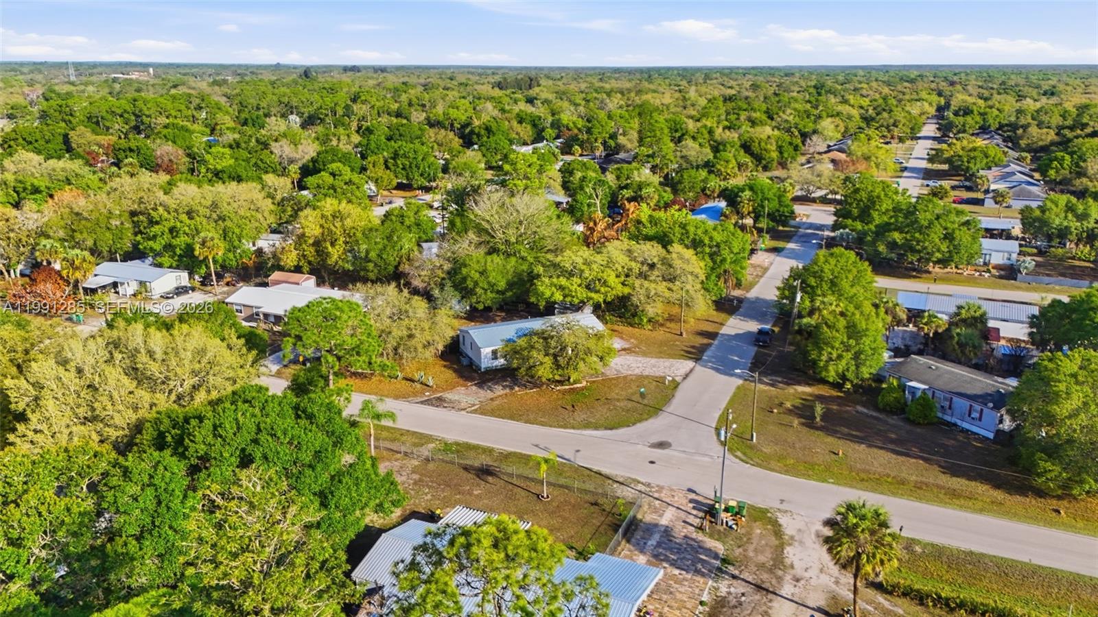 An aerial view shows a residential area with several houses surrounded by many trees — 740 bennett ave, La Belle FL 33935, LA BELLE, FL