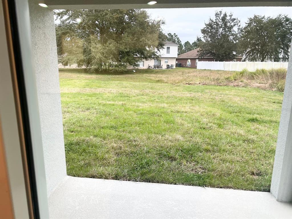 A view of a grassy backyard seen through a doorway or window — 709 VERSAILLES LANE, KISSIMMEE, FL