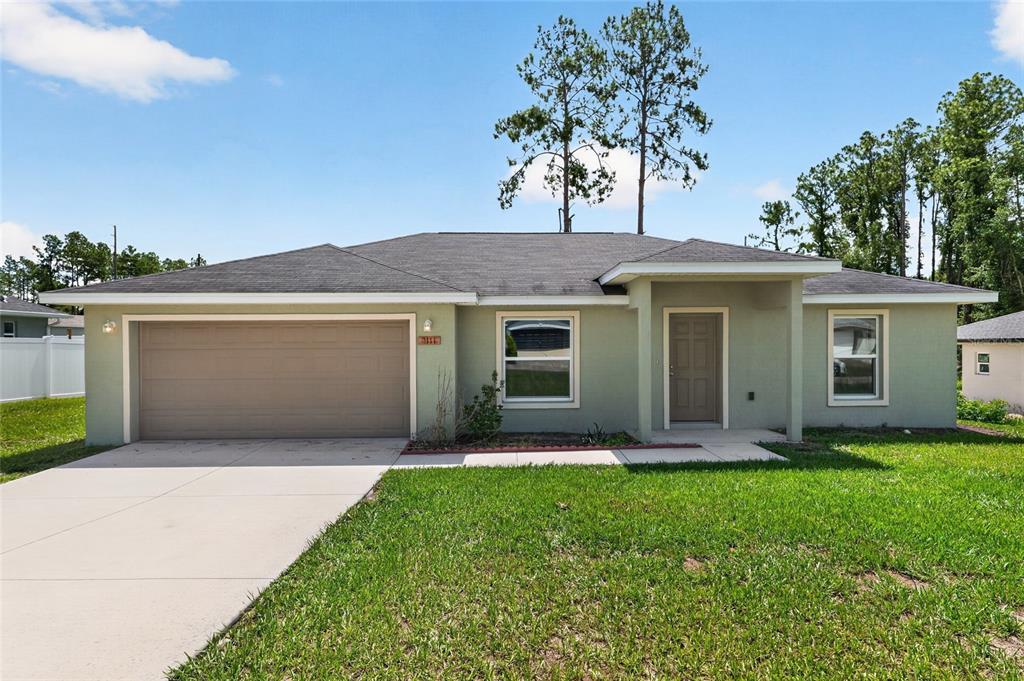 A single-story house with a light green exterior, a two-car garage, and a front lawn — 8111 SW 132ND LOOP, OCALA, FL