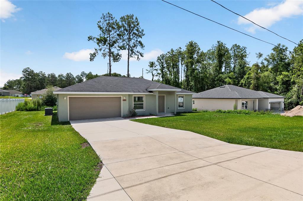 A single-story house with a two-car garage and a concrete driveway under a blue sky — 8111 SW 132ND LOOP, OCALA, FL