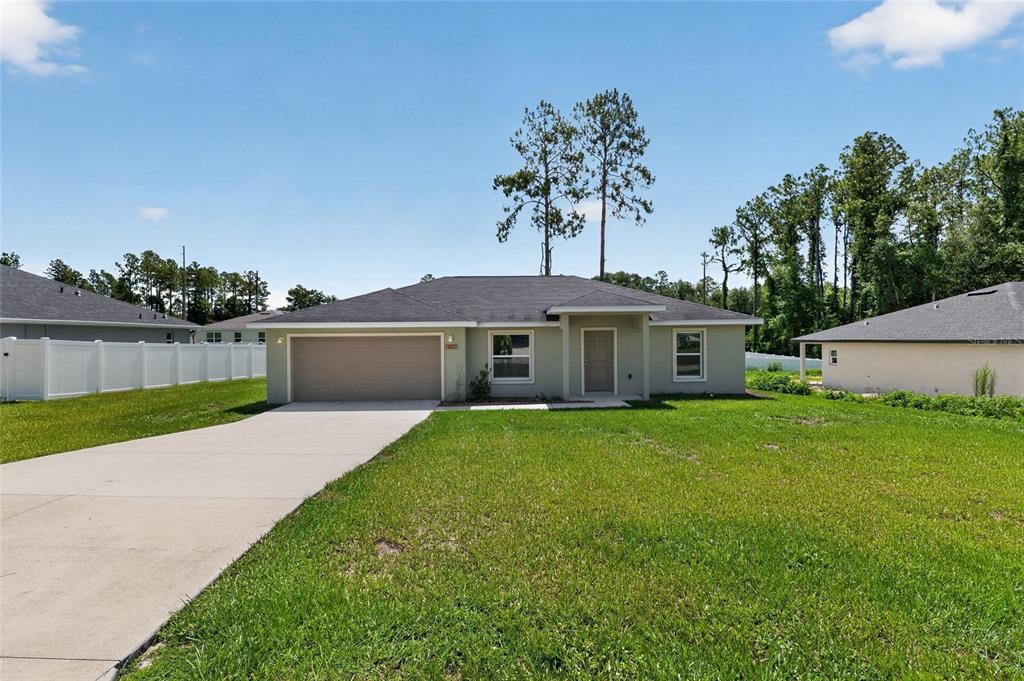 A single-story house with a two-car garage, a concrete driveway, and a grassy front yard — 8111 SW 132ND LOOP, OCALA, FL