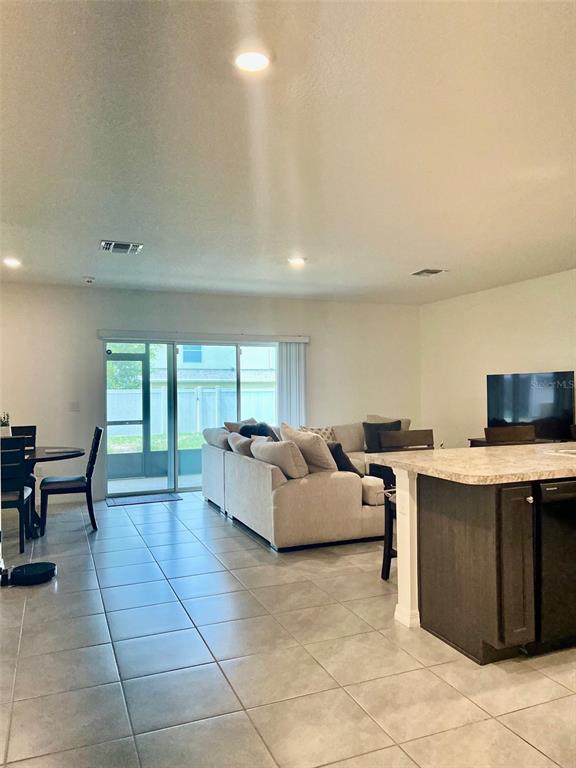 An open-concept living area features a kitchen island, a sectional sofa, and sliding glass doors — 9033 ALBA LANE, KISSIMMEE, FL