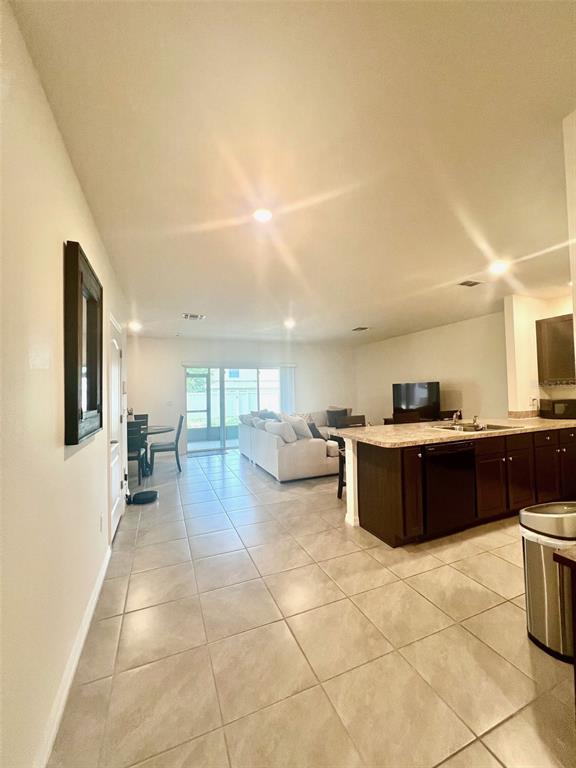 An open-concept kitchen and living area features tile flooring, dark cabinetry, and a sliding door — 9033 ALBA LANE, KISSIMMEE, FL
