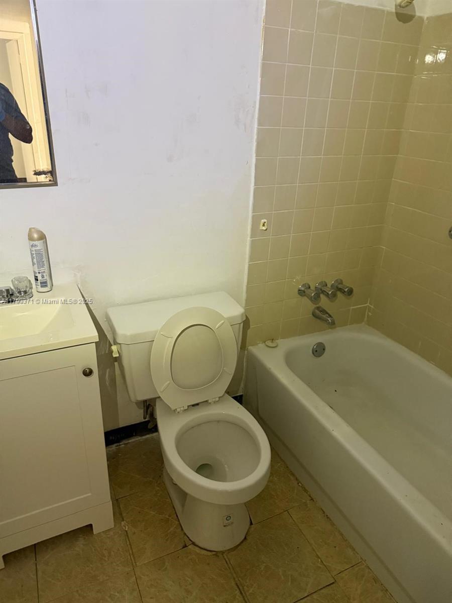 A bathroom features a white vanity, a toilet, and a bathtub with beige wall tiles — 1600 NW 4th Ave # 16A, Miami FL 33136, MIAMI, FL