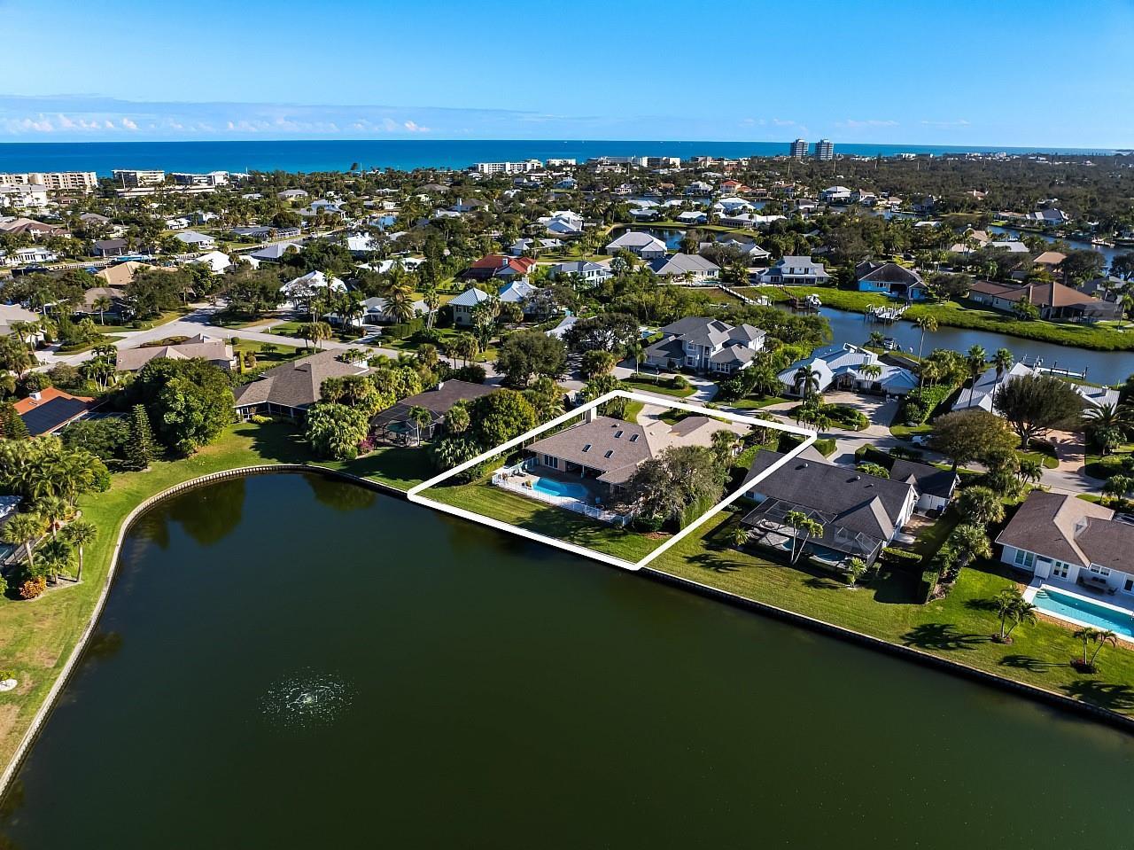 An aerial view shows a waterfront house with a pool and lawn in a neighborhood — 72 Cache Cay Drive, Vero Beach FL 32963, VERO BEACH, FL