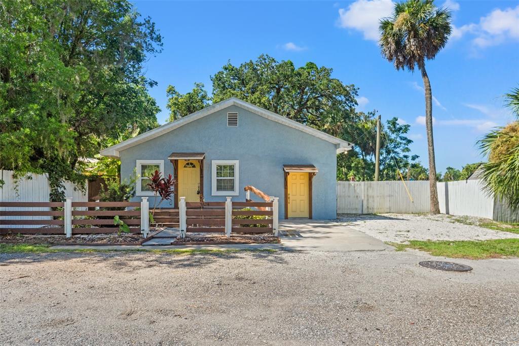A light blue house with two yellow doors stands behind a brown wooden fence — 5724 CASSON AVENUE, NEW PORT RICHEY, FL