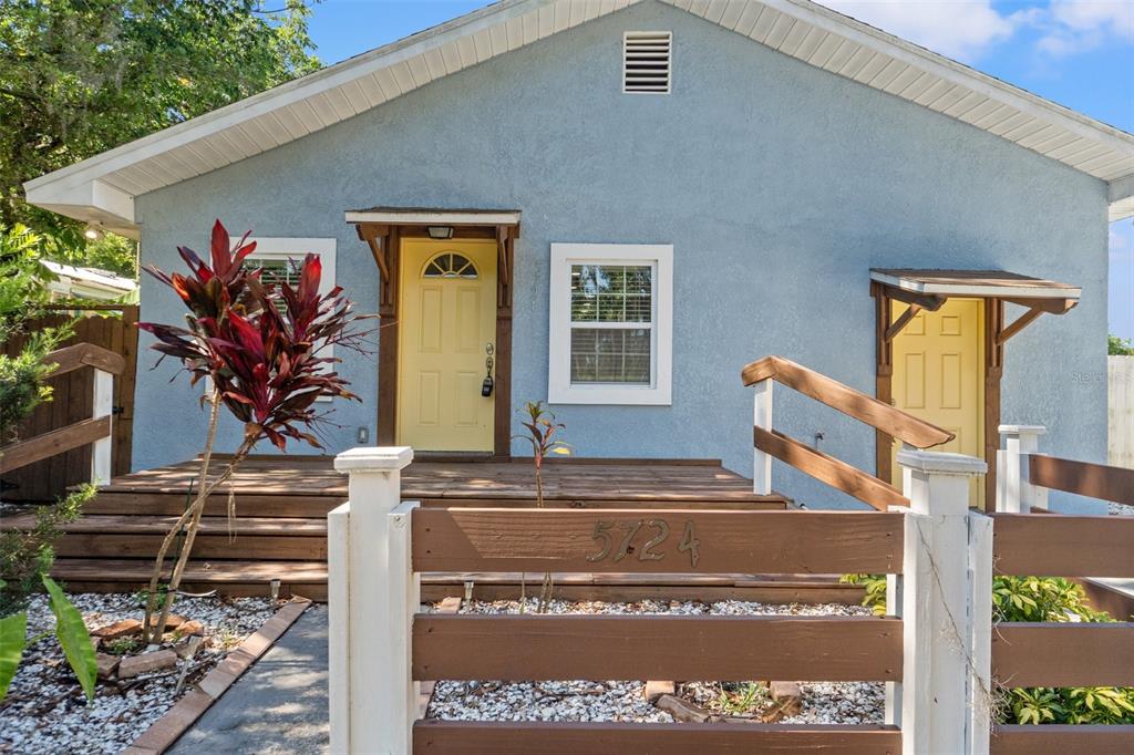 A light blue house features a wooden deck, two yellow doors, and a brown fence — 5724 CASSON AVENUE, NEW PORT RICHEY, FL