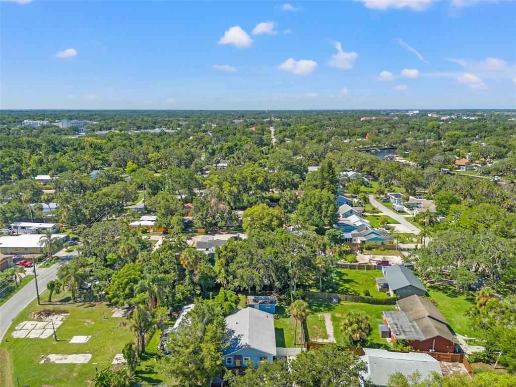 An aerial view shows a residential neighborhood with houses, trees, and streets under a blue sky — 5724 CASSON AVENUE, NEW PORT RICHEY, FL