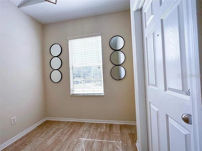 A small room features light-colored walls, wood-look tile flooring, a window, and wall-mounted circular mirrors — 21915 BELL LAKE ROAD UNIT 2, LAND O LAKES, FL