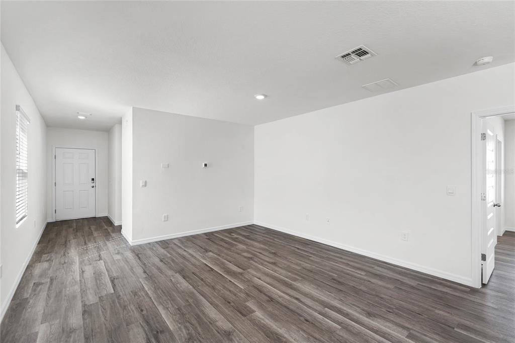 An empty room with white walls, wood-look flooring, and a white entry door — 1746 HUMMINGBIRD ROAD, WINTER HAVEN, FL