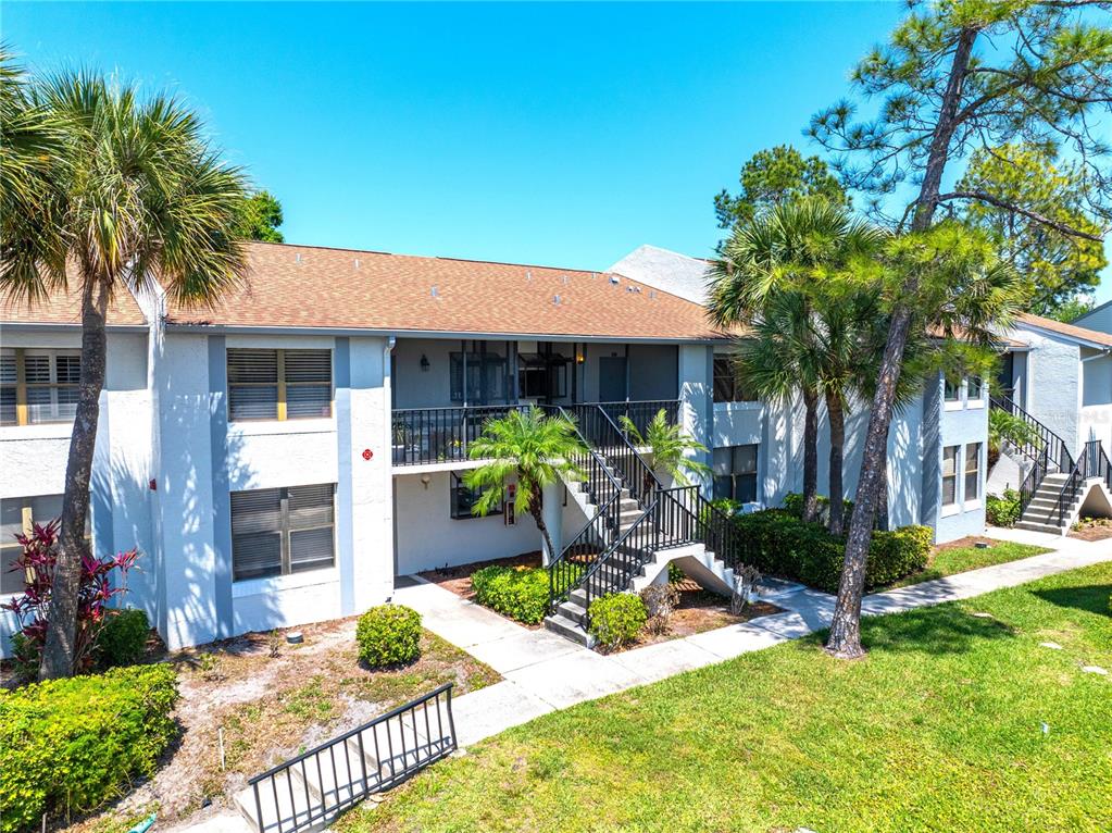 An exterior view of a two-story apartment building with a staircase leading to the balcony — 2017 SKIMMER CT W UNIT 424, CLEARWATER, FL