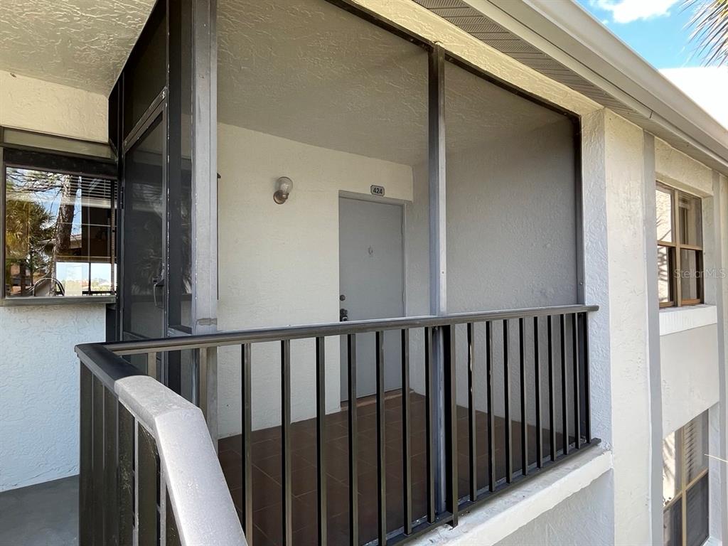 A screened-in balcony with a tiled floor and a gray entry door labeled 424 — 2017 SKIMMER CT W UNIT 424, CLEARWATER, FL
