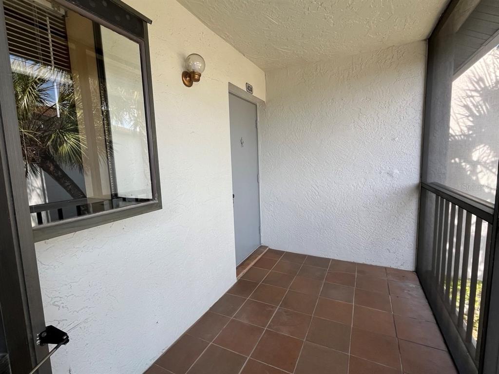 A covered entryway features a gray door, tiled flooring, and a screened-in wall — 2017 SKIMMER CT W UNIT 424, CLEARWATER, FL