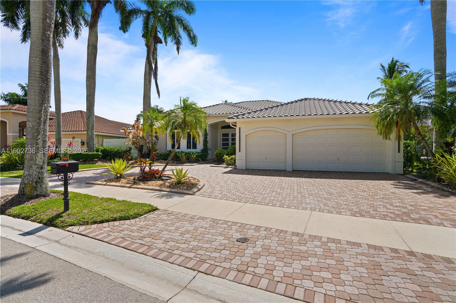 A single-story house features a paved driveway, a two-car garage, and several palm trees — 2569 Eagle Run Ln # 0, Weston FL 33327, WESTON, FL