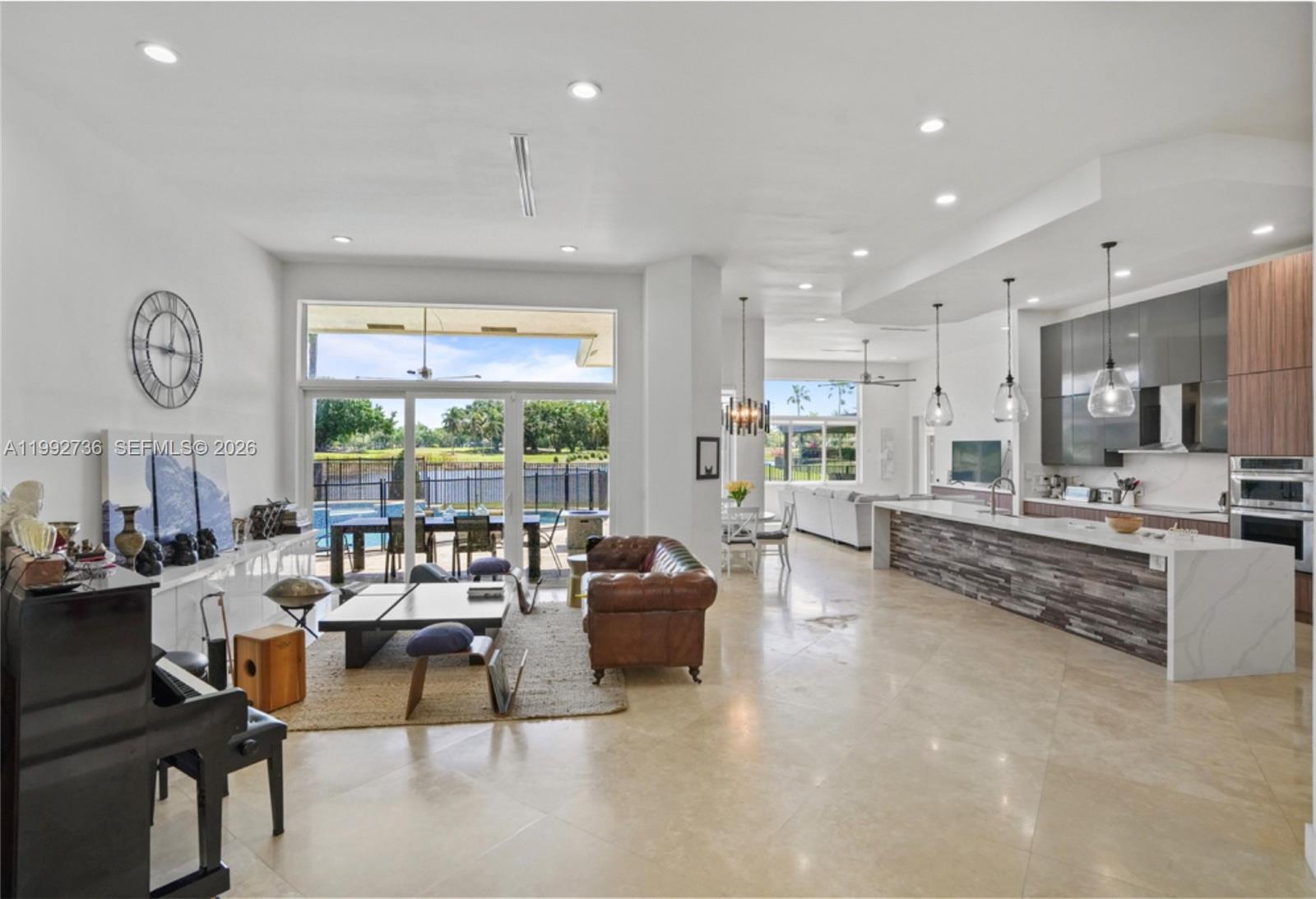 An open-concept living area features a kitchen with a stone island, piano, and pool view — 2569 Eagle Run Ln # 0, Weston FL 33327, WESTON, FL