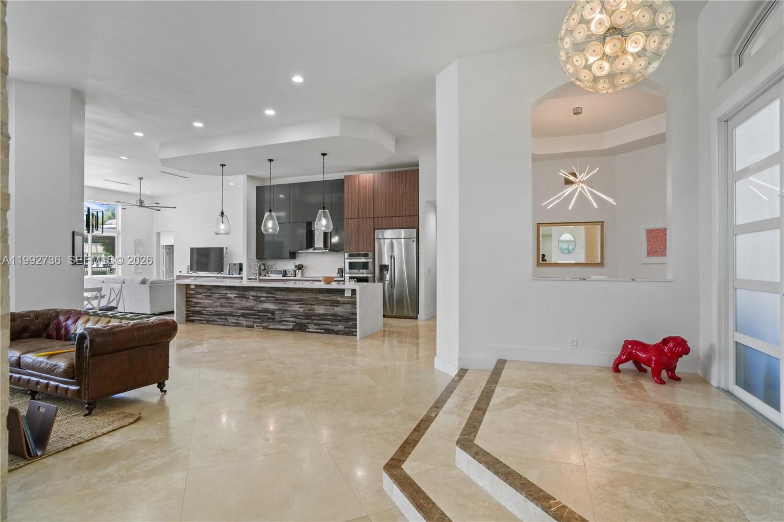 An open-concept living area features a kitchen with stone-faced island, tile floors, and modern lighting — 2569 Eagle Run Ln # 0, Weston FL 33327, WESTON, FL