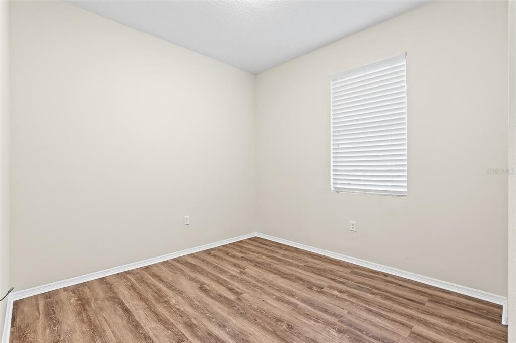 An empty room with light-colored walls, wood-look flooring, and a window with white blinds — 535 AEOLIAN DRIVE, NEW SMYRNA BEACH, FL