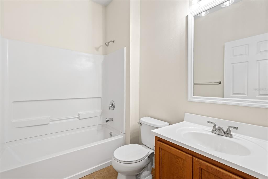 A bathroom features a white tub-shower combo, a toilet, and a wooden vanity with sink — 535 AEOLIAN DRIVE, NEW SMYRNA BEACH, FL