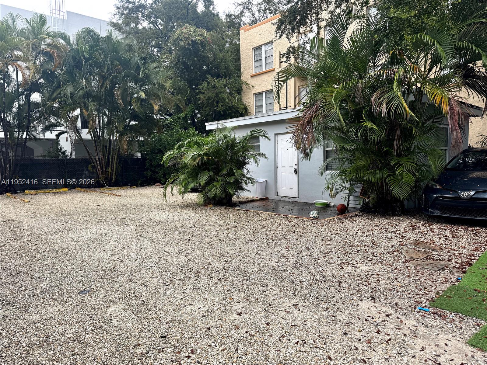 A two-story, light gray stucco house with a gravel driveway and a small covered storage area — 529 SW 3rd St, Miami FL 33130, MIAMI, FL