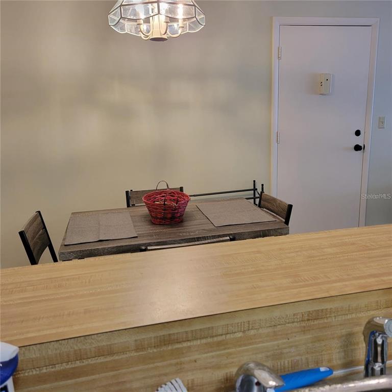 A dining area features a wooden table with chairs beneath a decorative light fixture — 3275 BENEVA ROAD UNIT 104, SARASOTA, FL