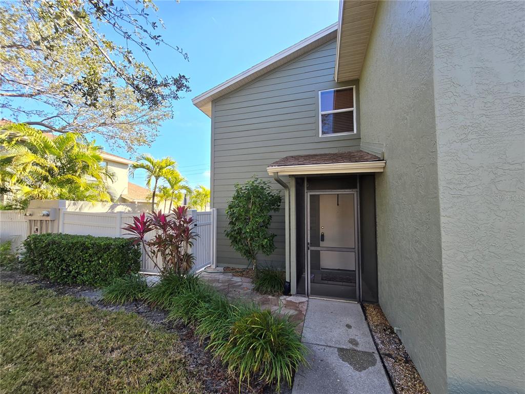 The exterior of a two-story home features green siding, a stone walkway, and a screen door — 4181 CENTER POINTE CIRCLE UNIT 91B, SARASOTA, FL