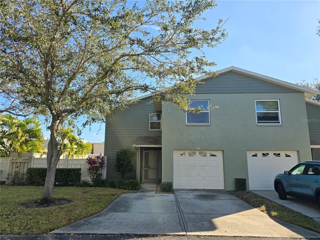 A two-story townhouse with a light green exterior, a driveway, and a single-car garage — 4181 CENTER POINTE CIRCLE UNIT 91B, SARASOTA, FL