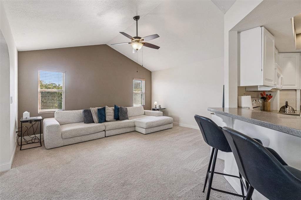 A living room with a vaulted ceiling, beige carpet, a sectional sofa, and a breakfast bar — 4181 CENTER POINTE CIRCLE UNIT 91B, SARASOTA, FL